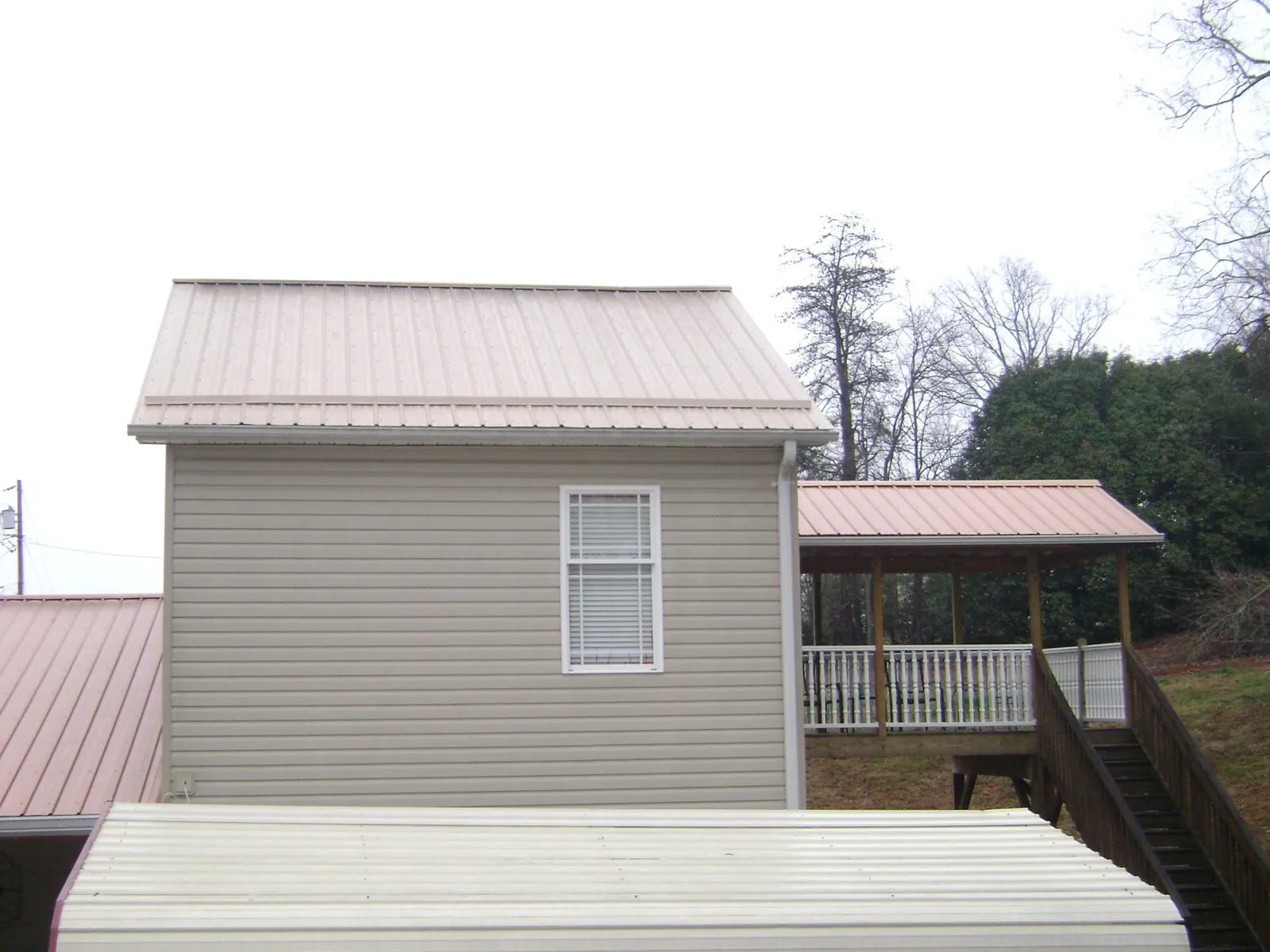Tan metal roofs on a two story addition and attached porch, from a Roof Replacement job in Snow Hill